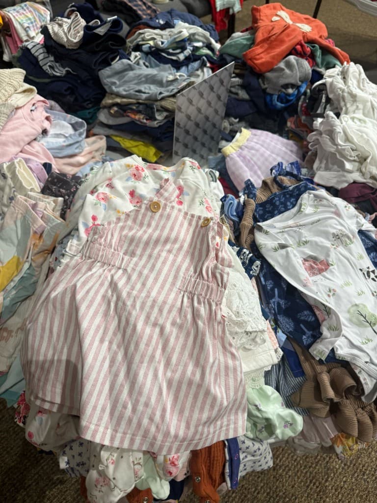 Colorful pile of infant clothing with floral prints and stripes