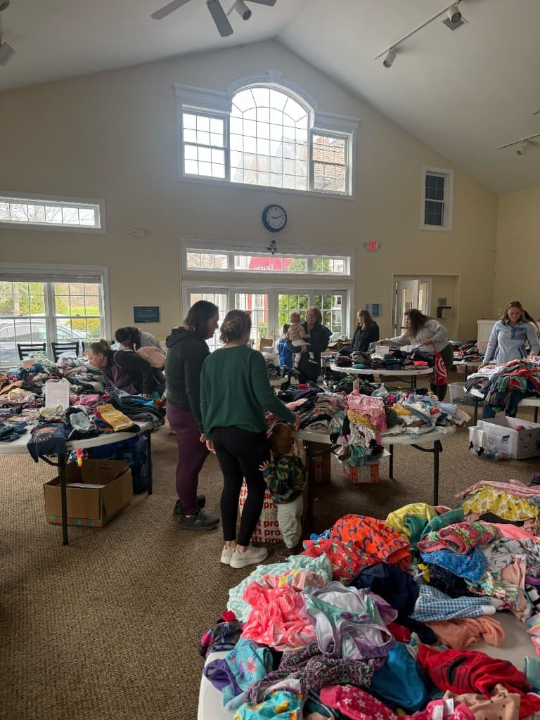 Parents and children looking through colorful piles of donated clothing