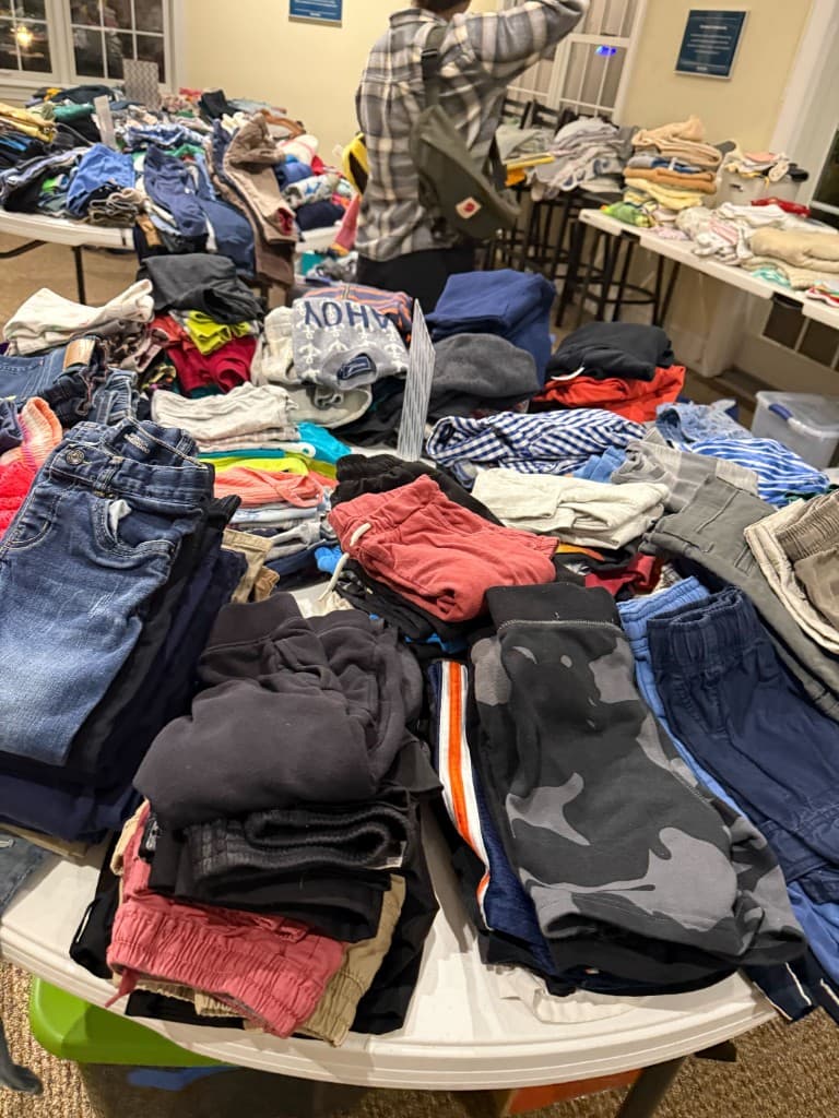 Volunteer organizing clothing between tables at the pop-up