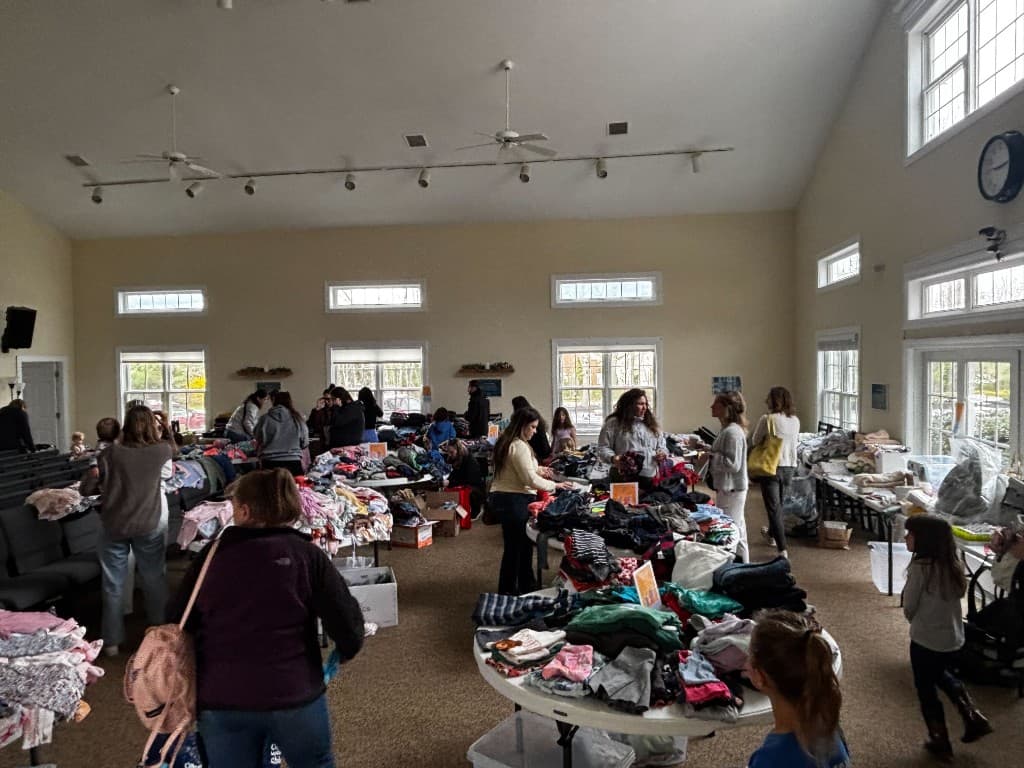 Wide view of the community hall filled with clothing tables and attendees