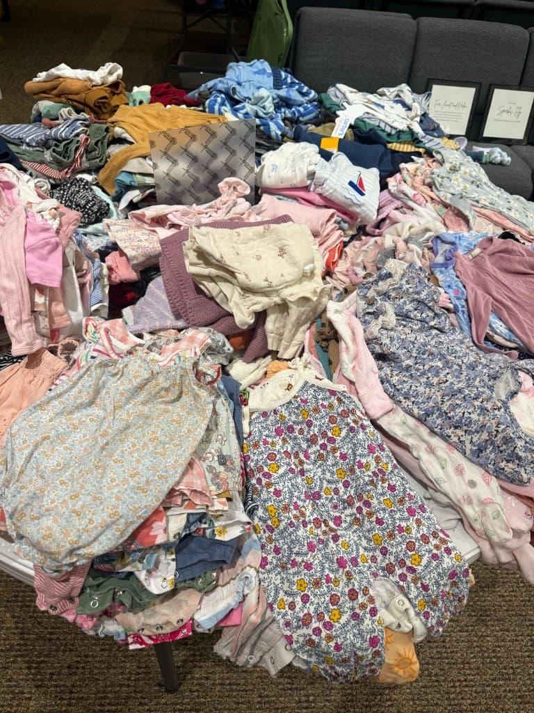 Bright summer children's clothing piled on a round table near a shoe display