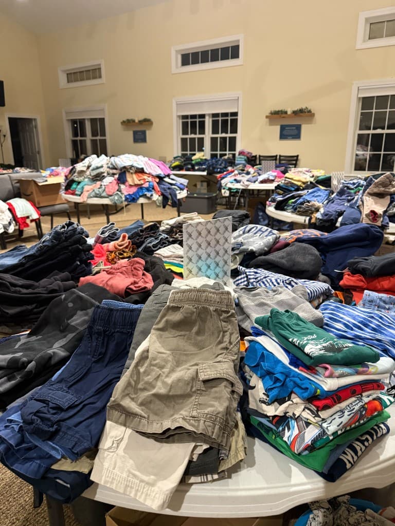 Round tables covered with neatly folded children's shirts and pants